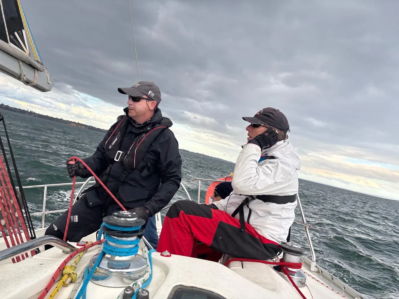 Two sailors aboard a yacht on Port Phillip Bay under cloudy skies